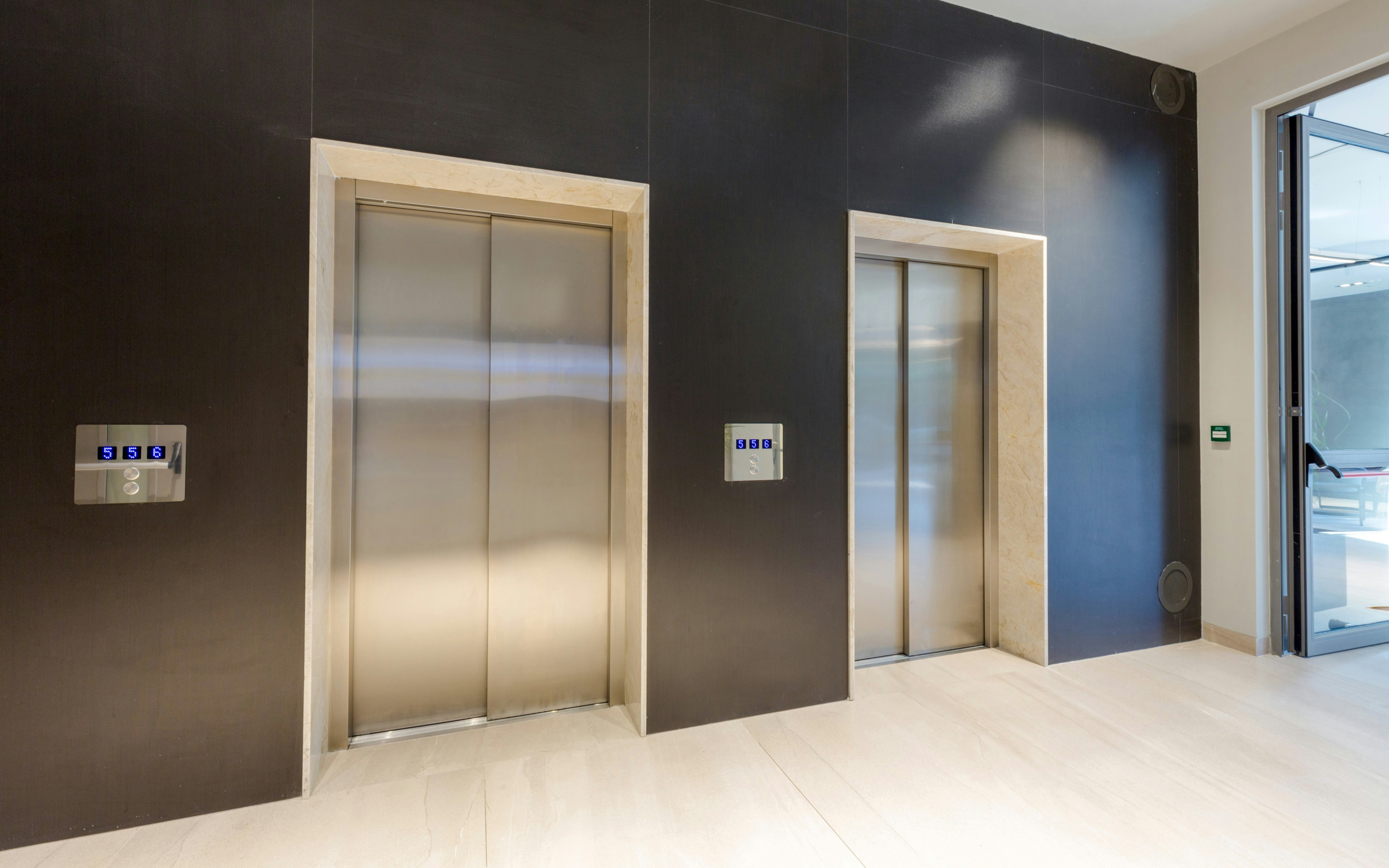 Lobby with two closed elevator doors and control panels.