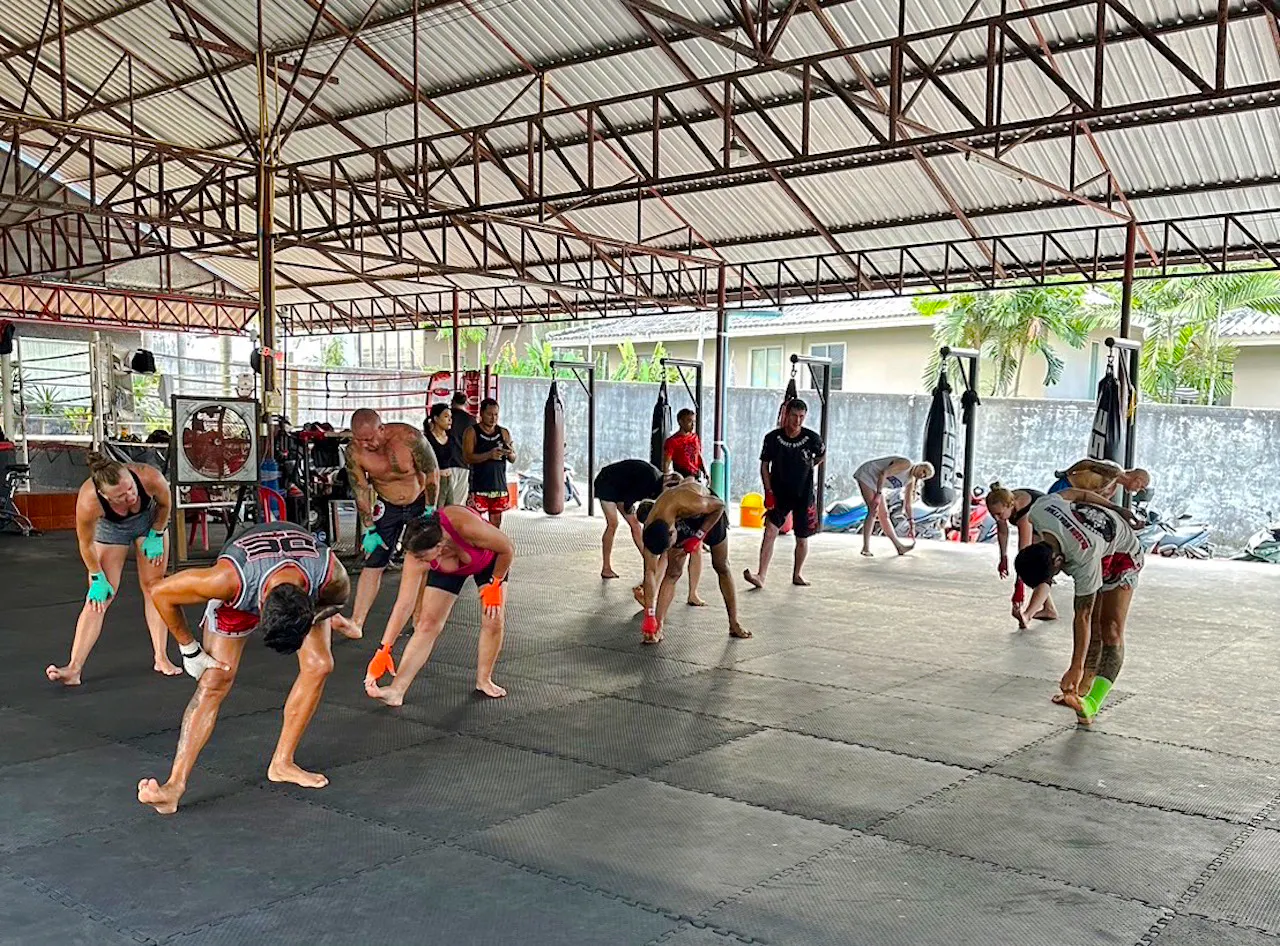 Beginners practicing Muay Thai stretches in a Phuket training gym.