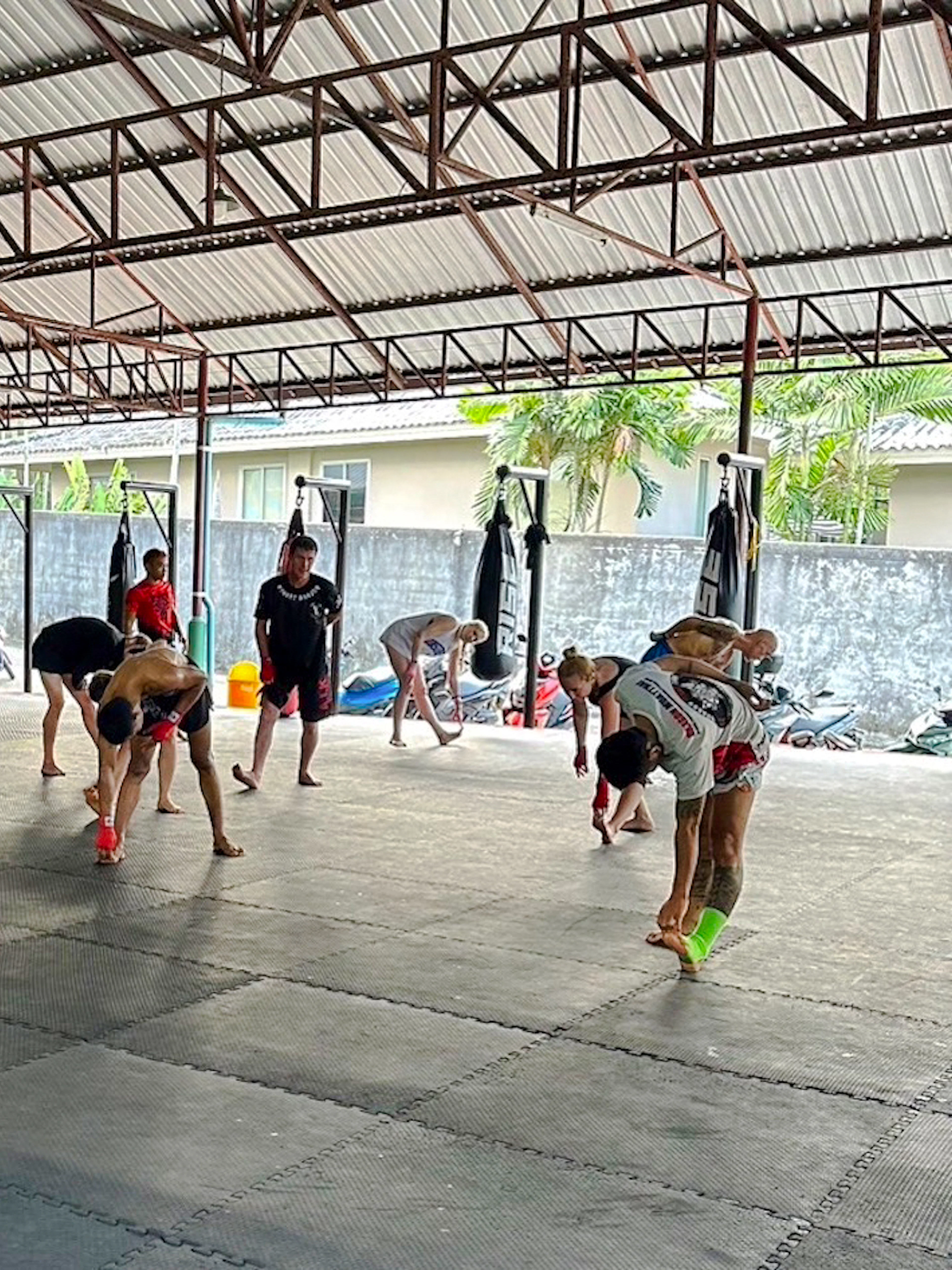 Beginners practicing Muay Thai stretches in a Phuket training gym.