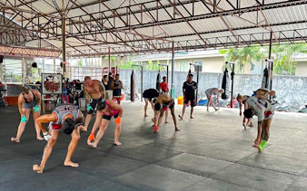 Beginners practicing Muay Thai stretches in a Phuket training gym.