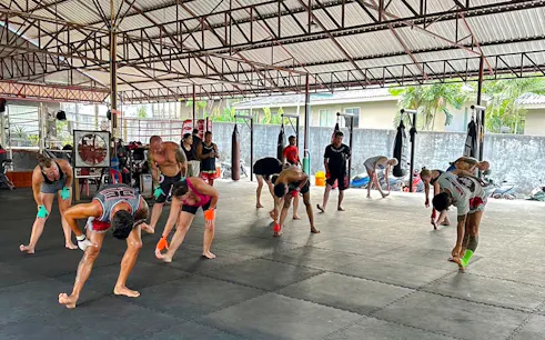 Beginners practicing Muay Thai stretches in a Phuket training gym.