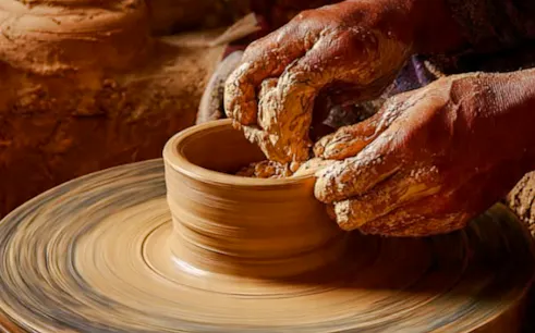 Hands shaping clay on a pottery wheel in Al Haouz, Marrakesh workshop.