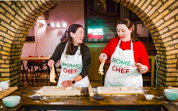 Participants making pasta at a Spritz & Spaghetti Tipsy Cooking Class in Rome.