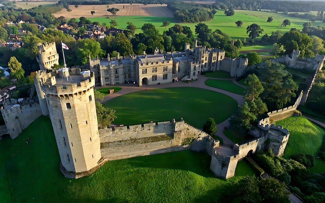 Aerial view of Warwick Castle surrounded by lush greenery, part of the Stratford, Oxford, Cotswolds tour.