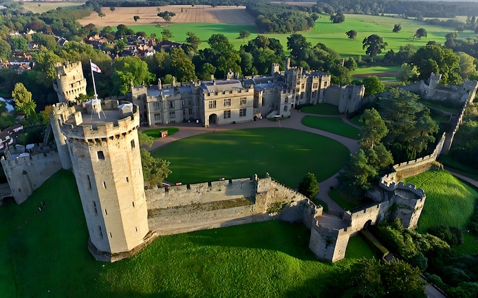 Aerial view of Warwick Castle surrounded by lush greenery, part of the Stratford, Oxford, Cotswolds tour.