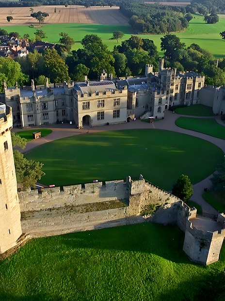 Aerial view of Warwick Castle surrounded by lush greenery, part of the Stratford, Oxford, Cotswolds tour.