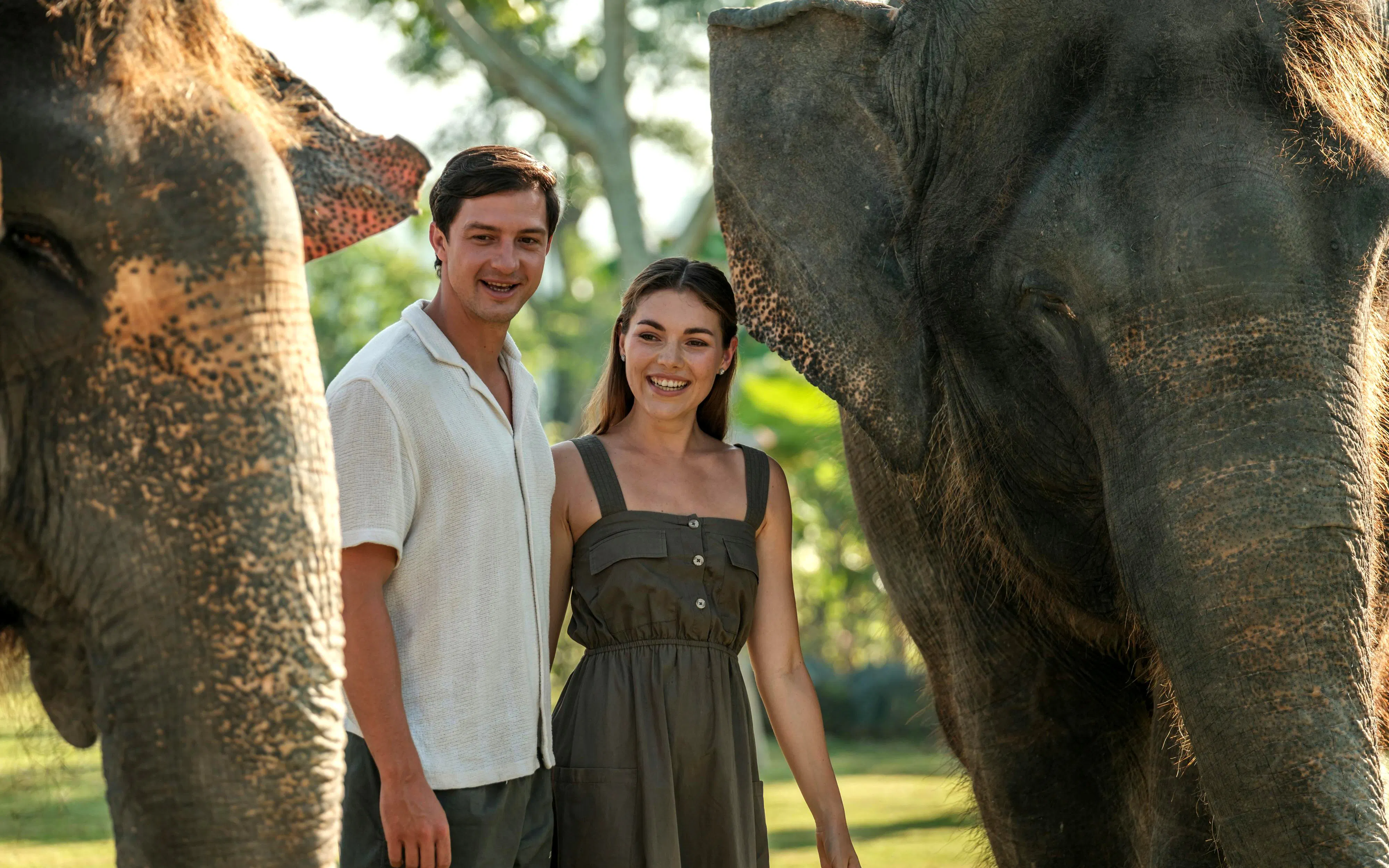 Couple standing between elephants during Elephant Explorer tour in Bali.