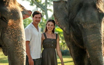 Couple standing between elephants during Elephant Explorer tour in Bali.
