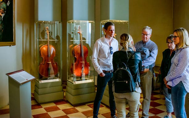 Tourists viewing cellos in Gallerie dell'Accademia, Venice.