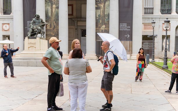 Guide discussing artwork with tourists outside Prado Museum, Madrid.
