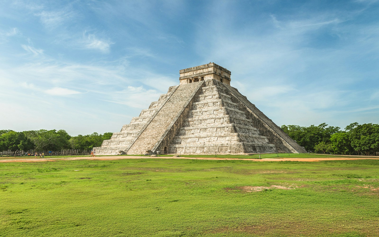 Chichen Itza Pyramid of Kukulcan in Yucatan, Mexico, with tourists exploring the ancient Mayan site.