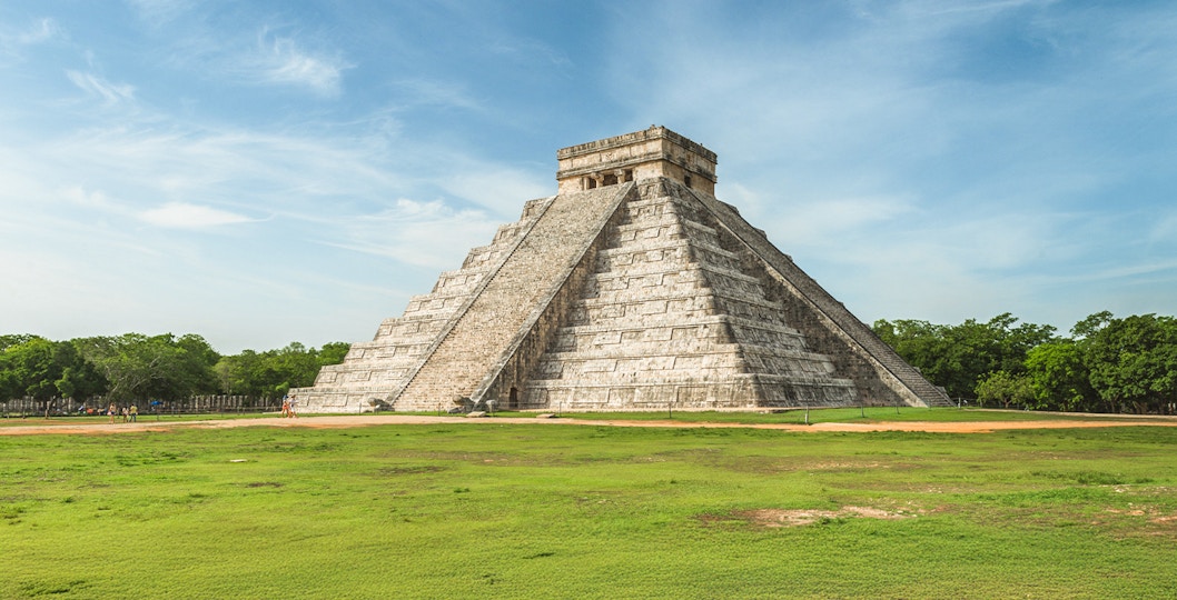 Chichen Itza Pyramid of Kukulcan with tourists exploring the ancient Mayan site in Mexico.