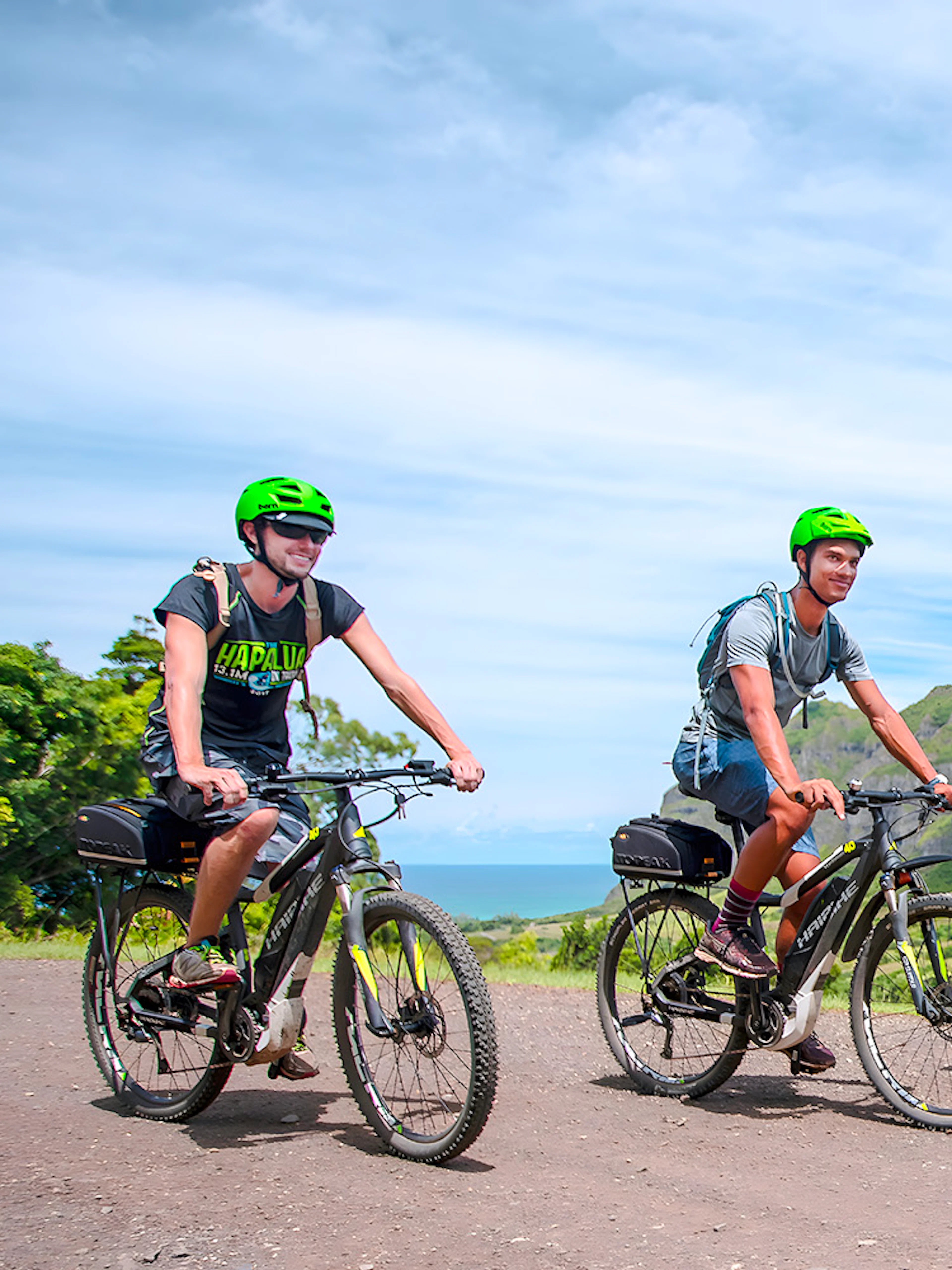 Novice riders on e-bikes touring Kualoa Ranch with lush mountains in the background.