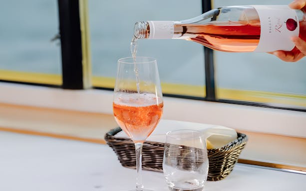Pouring rosé wine into a glass on a Danube cruise in Budapest.