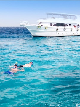 Friends snorkelling near a boat in the Red Sea during a Dolphin Watching Tour, Hurghada.