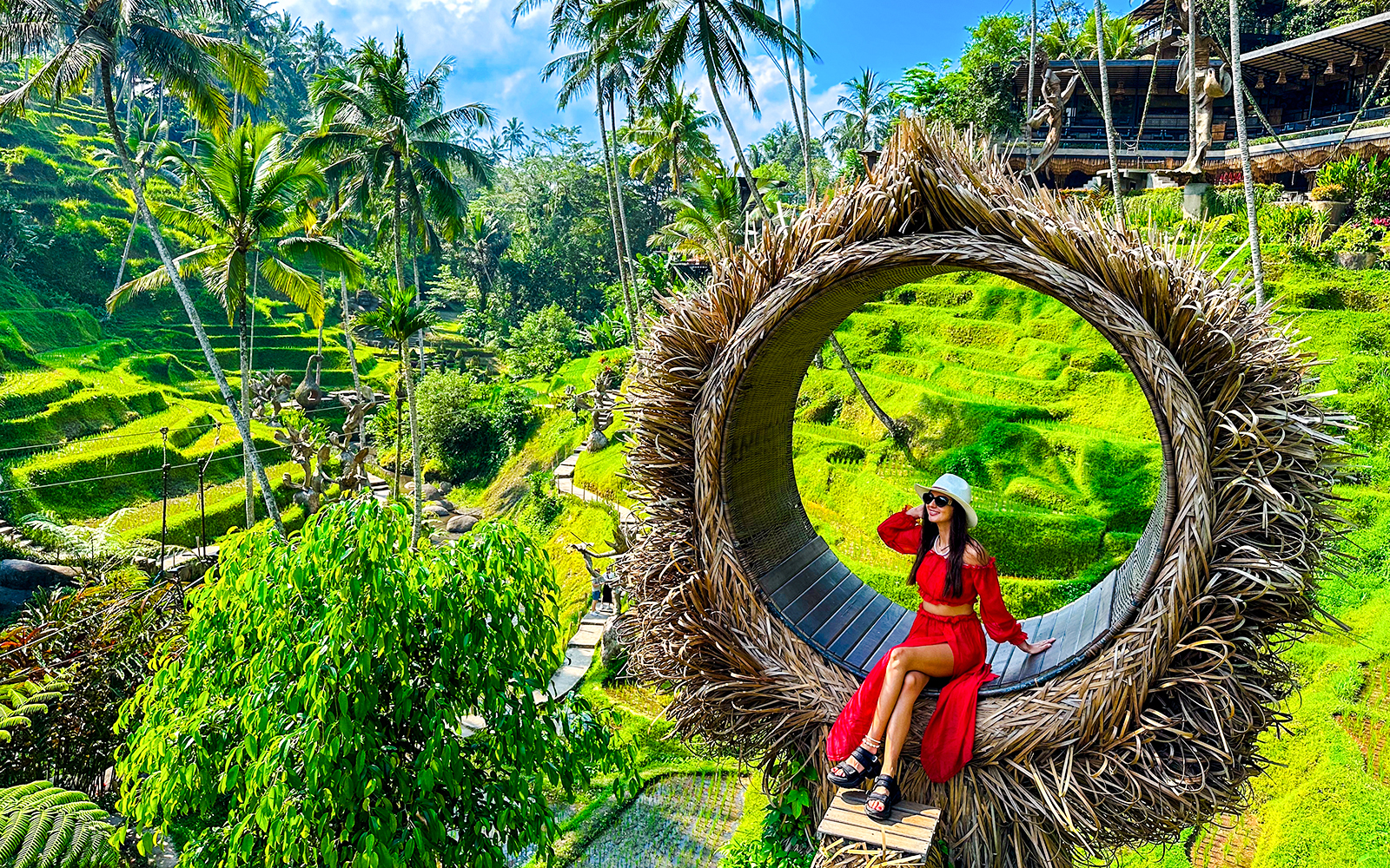 Woman sitting on a large nest swing overlooking Bali's lush rice terraces.