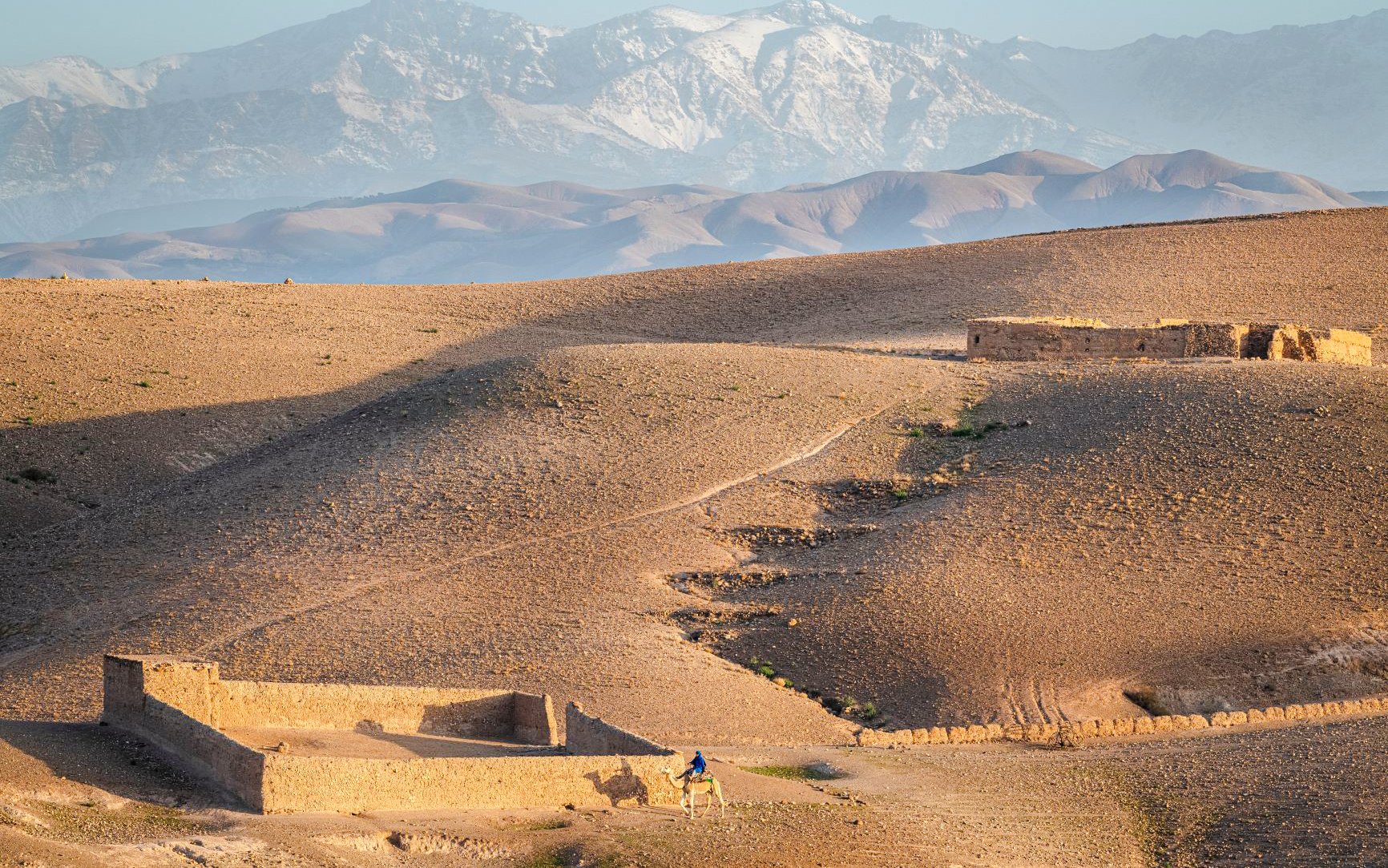 Quad biking in Agafay Desert with Atlas Mountains in the background.