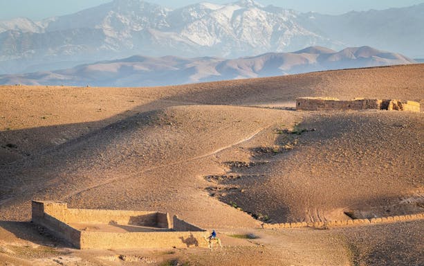 Quad biking in Agafay Desert with Atlas Mountains in the background.