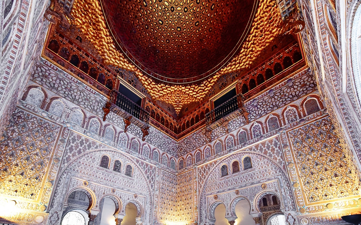 Alcazar of Seville's intricate interior architecture with detailed arches and ornate ceiling.