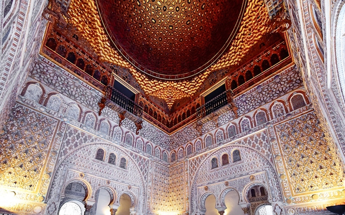 Alcazar of Seville's intricate interior architecture with detailed arches and ornate ceiling.