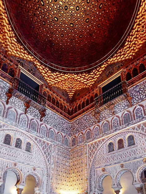 Alcazar of Seville's intricate interior architecture with detailed arches and ornate ceiling.