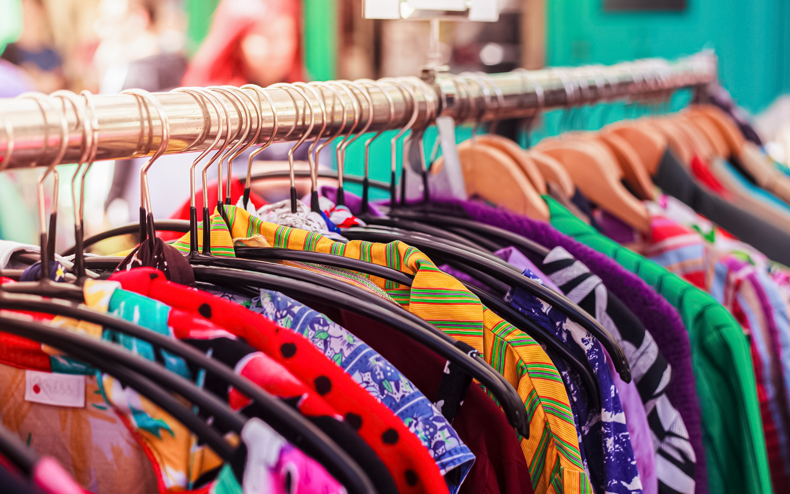 Street shop displaying vintage clothing in a bustling market setting.