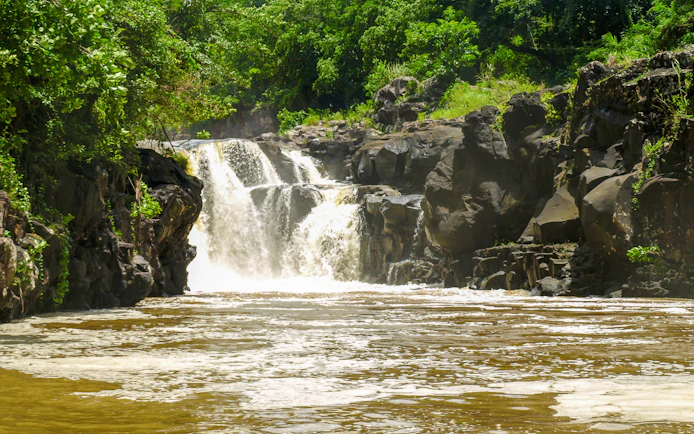 Waterfall at the Grand River South East estuary, Mauritius, surrounded by lush greenery.