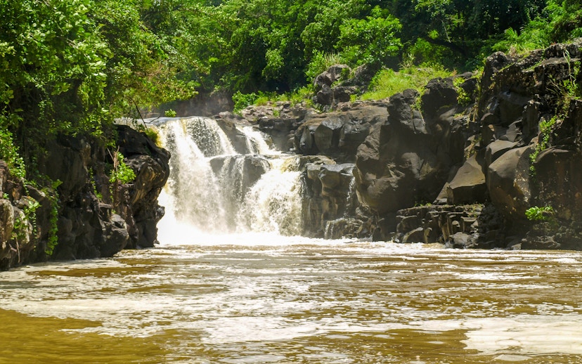 Waterfall at the Grand River South East estuary, Mauritius, surrounded by lush greenery.