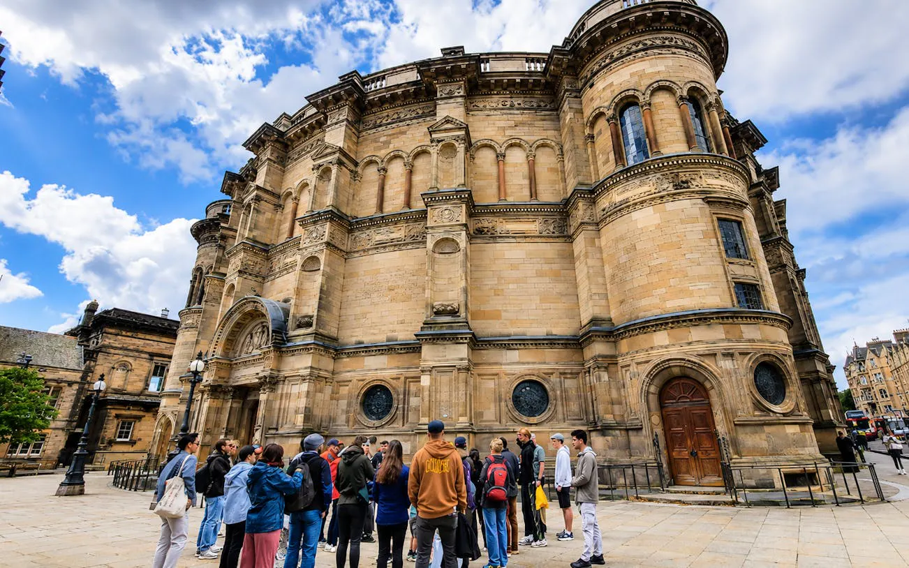 Group of tourists on a guided walking tour in front of a historic building in Edinburgh Old Town.