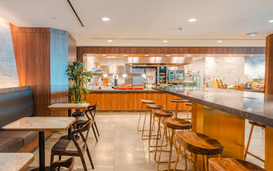 Pantry area at Plaza Premium Lounge, Terminal 3, Toronto Pearson Airport, featuring seating and food stations.