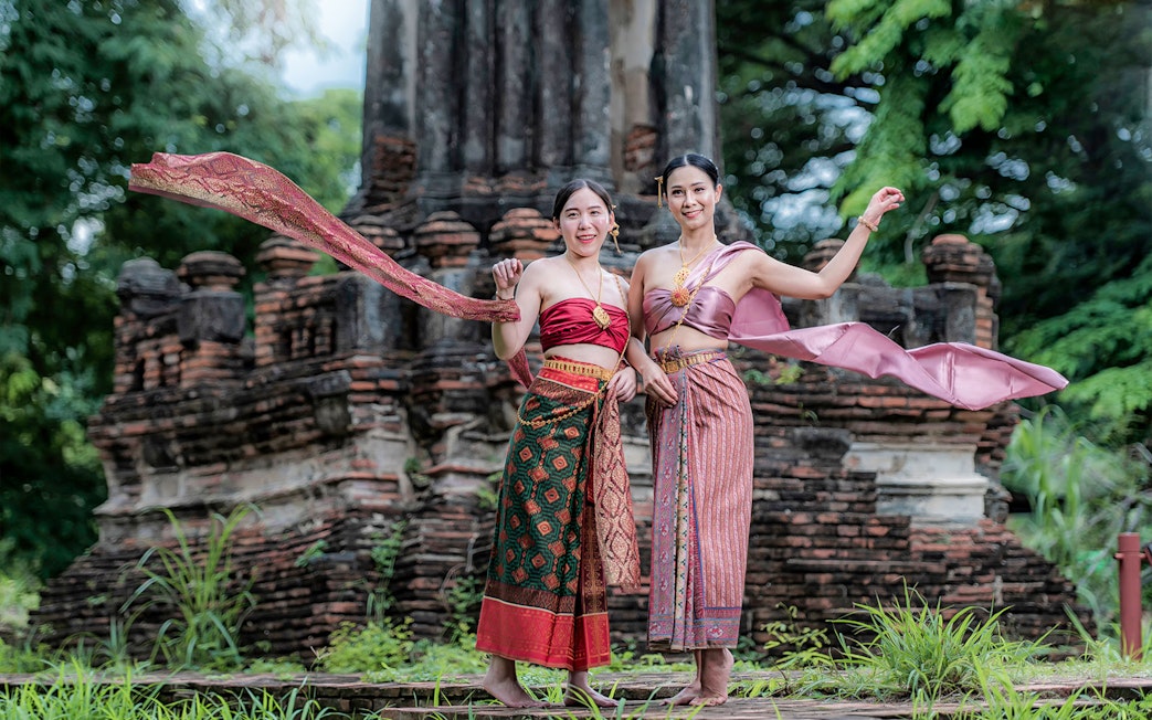 Women in traditional attire at ancient ruins during the Ancient City & Erawan Museum tour.