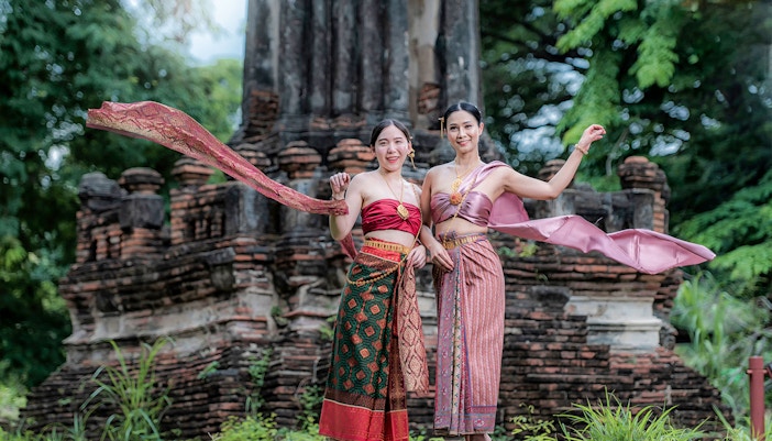 Women in traditional attire at ancient ruins during the Ancient City & Erawan Museum tour.