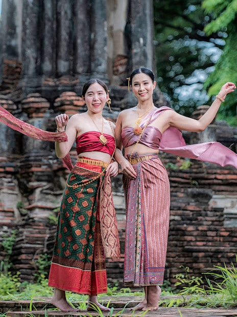 Women in traditional attire at ancient ruins during the Ancient City & Erawan Museum tour.