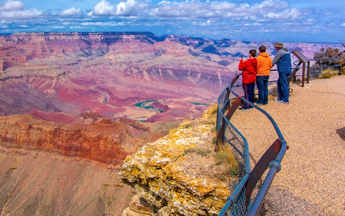 Visitors at Grand Canyon South Rim overlook vast canyon landscape.