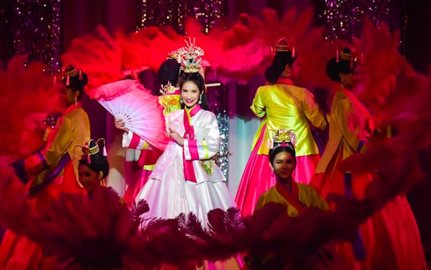 Performers in traditional costumes at Golden Dome Cabaret Show, holding pink fans.