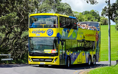 Auckland Explorer Bus on a sunny day with tourists on the upper deck.