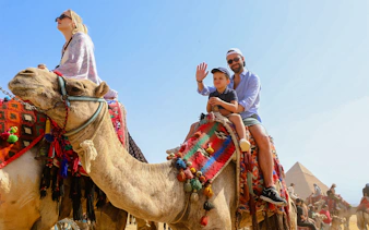 Tourists riding camels near the Giza Pyramids and Sphinx in Egypt.