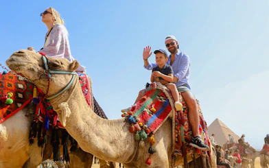 Tourists riding camels near the Giza Pyramids and Sphinx in Egypt.