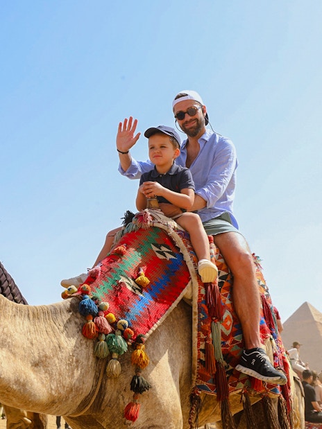 Tourists riding camels near the Giza Pyramids and Sphinx in Egypt.