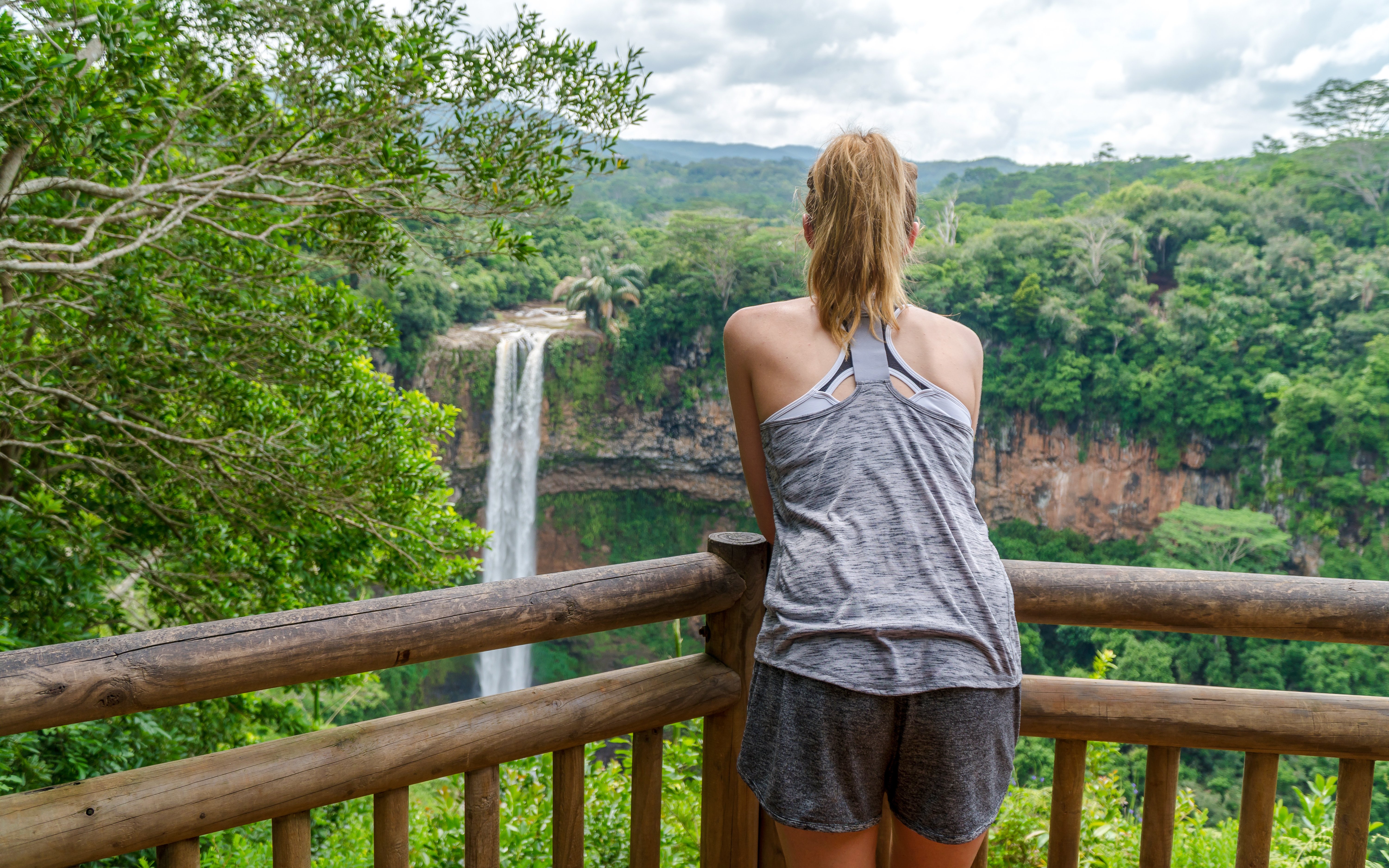 Person viewing Chamarel Waterfall from a wooden lookout, Mauritius.