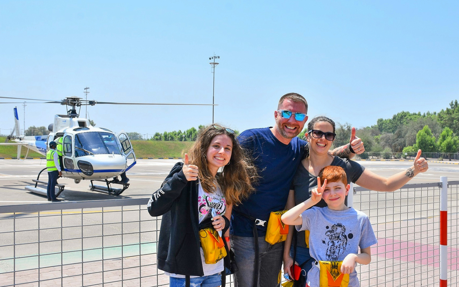 Family posing in front of a helicopter at a helipad in Dubai.