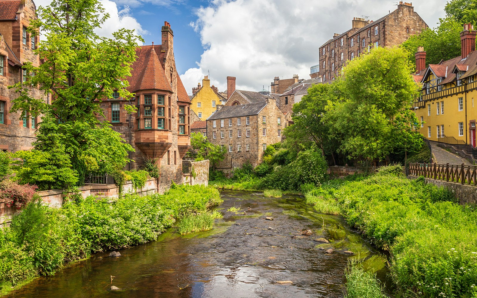 Dean Village, Edinburgh, with historic stone buildings and lush greenery along the Water of Leith.