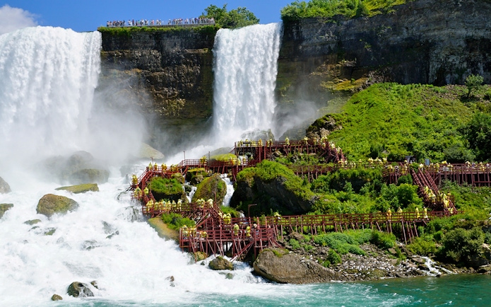 Visitors on wooden walkways at Niagara Cave of the Winds near waterfalls.