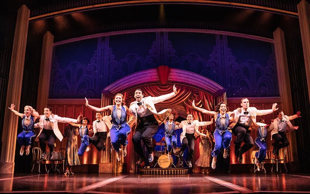 Performers in mid-air during a musical number from "Some Like it Hot" on stage.