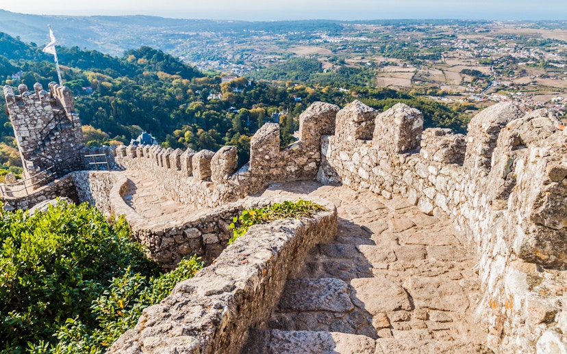 Stone pathway along the walls of Moorish Castle, Sintra, with scenic valley view.