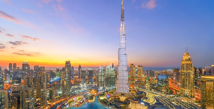 Burj Khalifa towering over Dubai skyline at sunset.