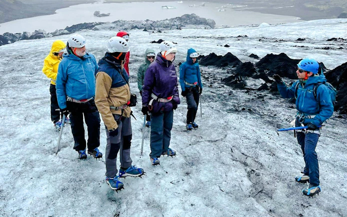 Guests hiking on Sólheimajökull Glacier with a guide during a small group tour in Iceland.
