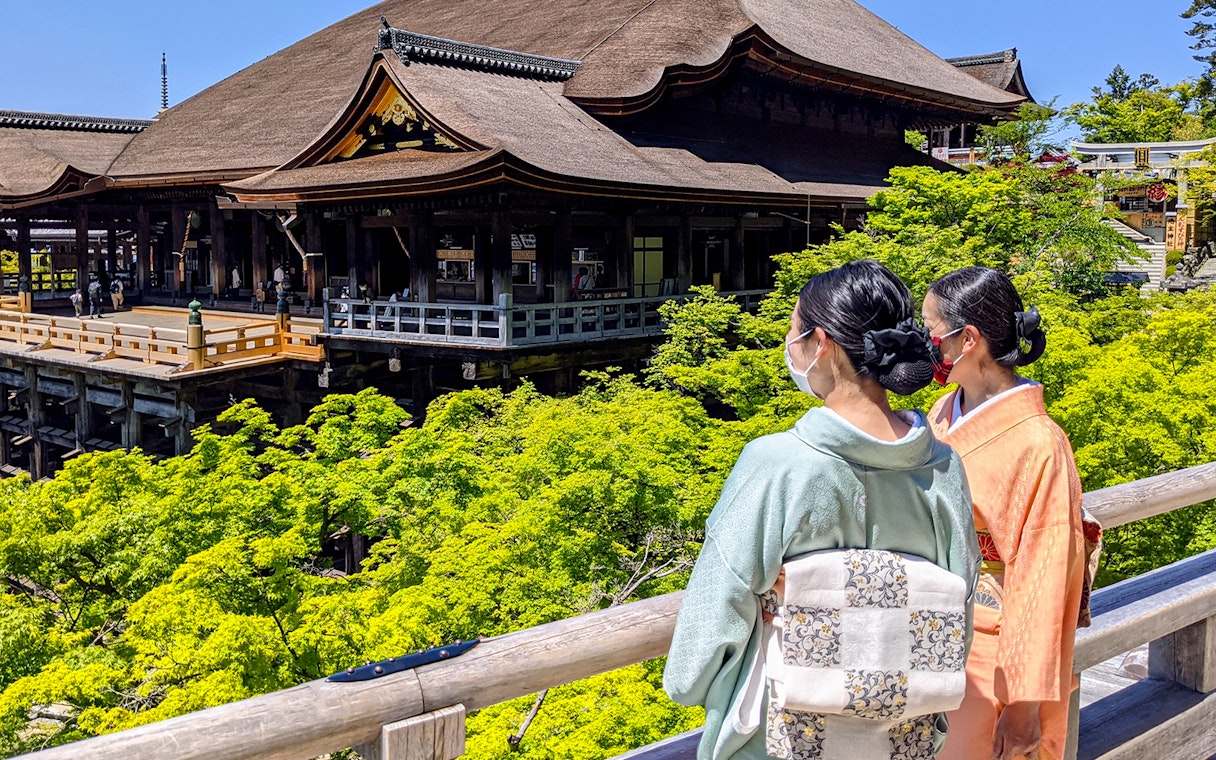 Two people in traditional attire overlooking Kiyomizu-dera Temple in Kyoto.