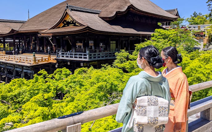 Two people in traditional attire overlooking Kiyomizu-dera Temple in Kyoto.
