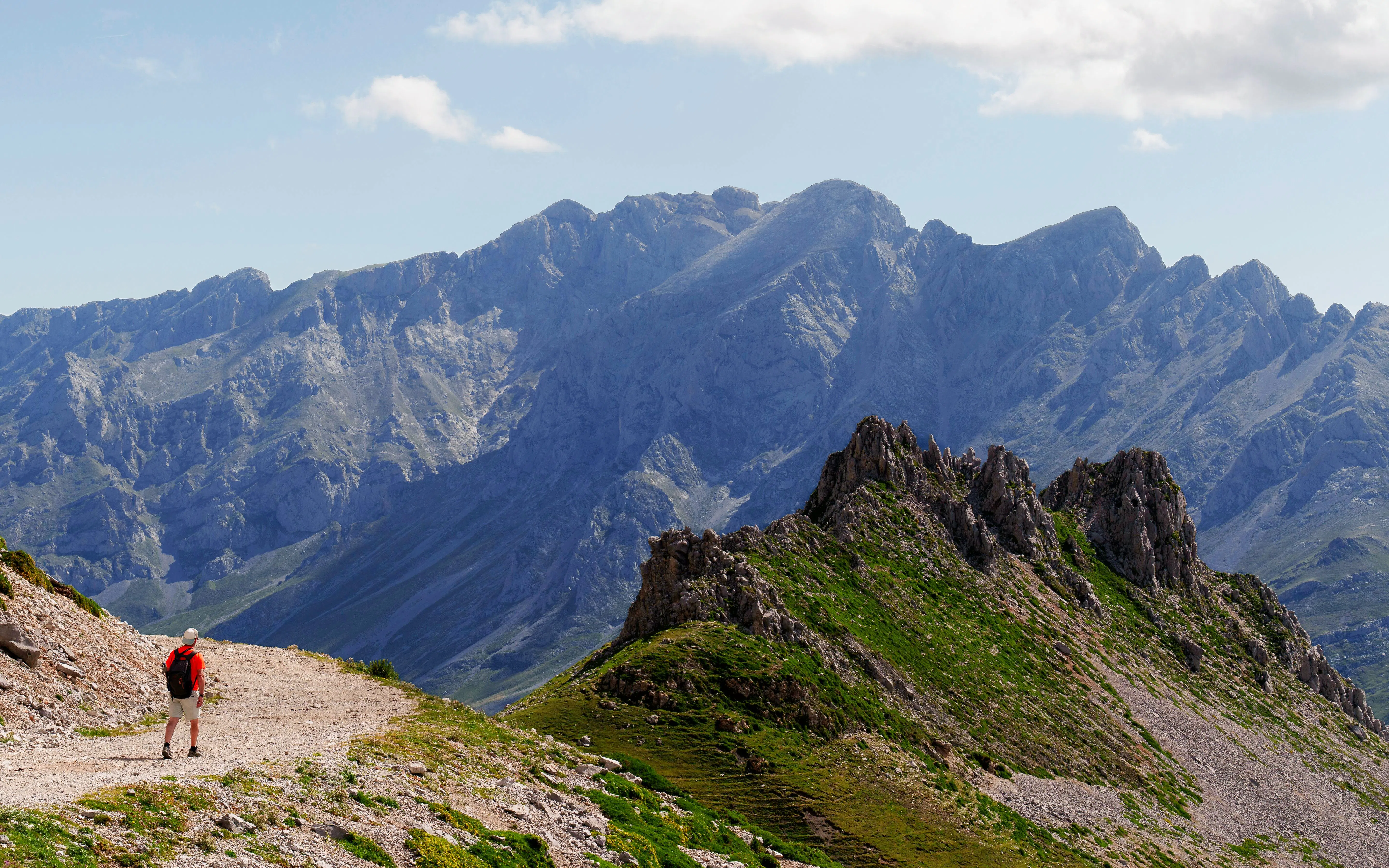 Hiker on Mirador del Cable to Espinama Trail with Picos de Europa mountains, Fuente De, Spain.